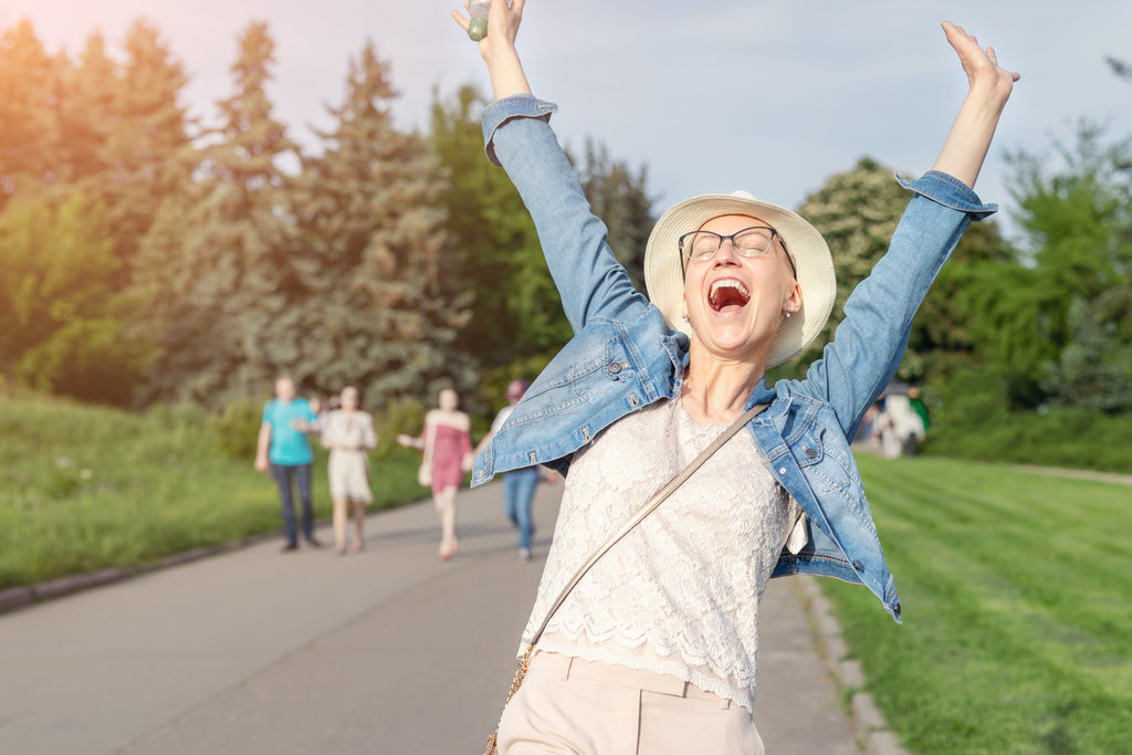 Woman with arms raised in a park, smiling